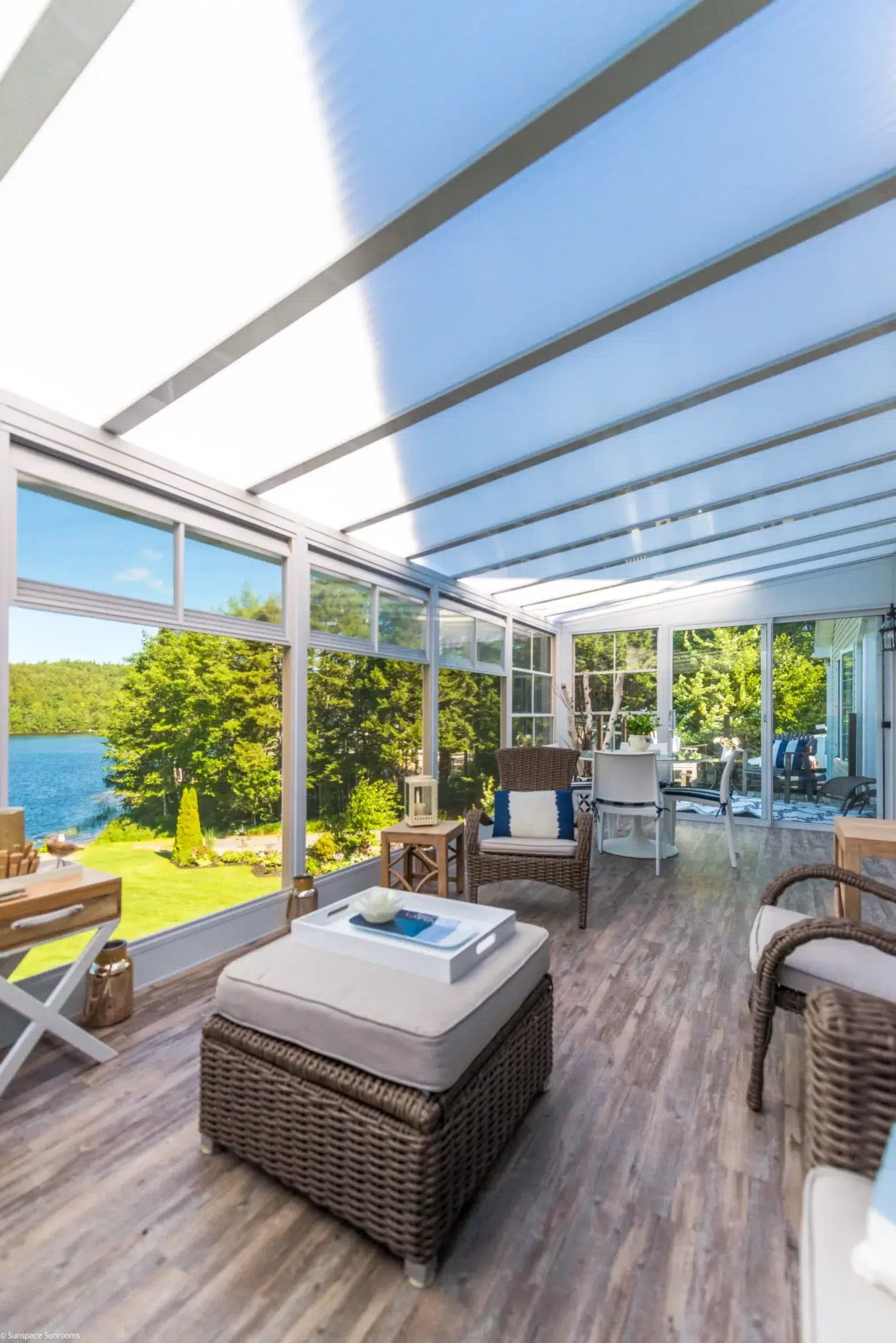 A bright, comfortable sunroom with wicker furniture overlooking a scenic lake.