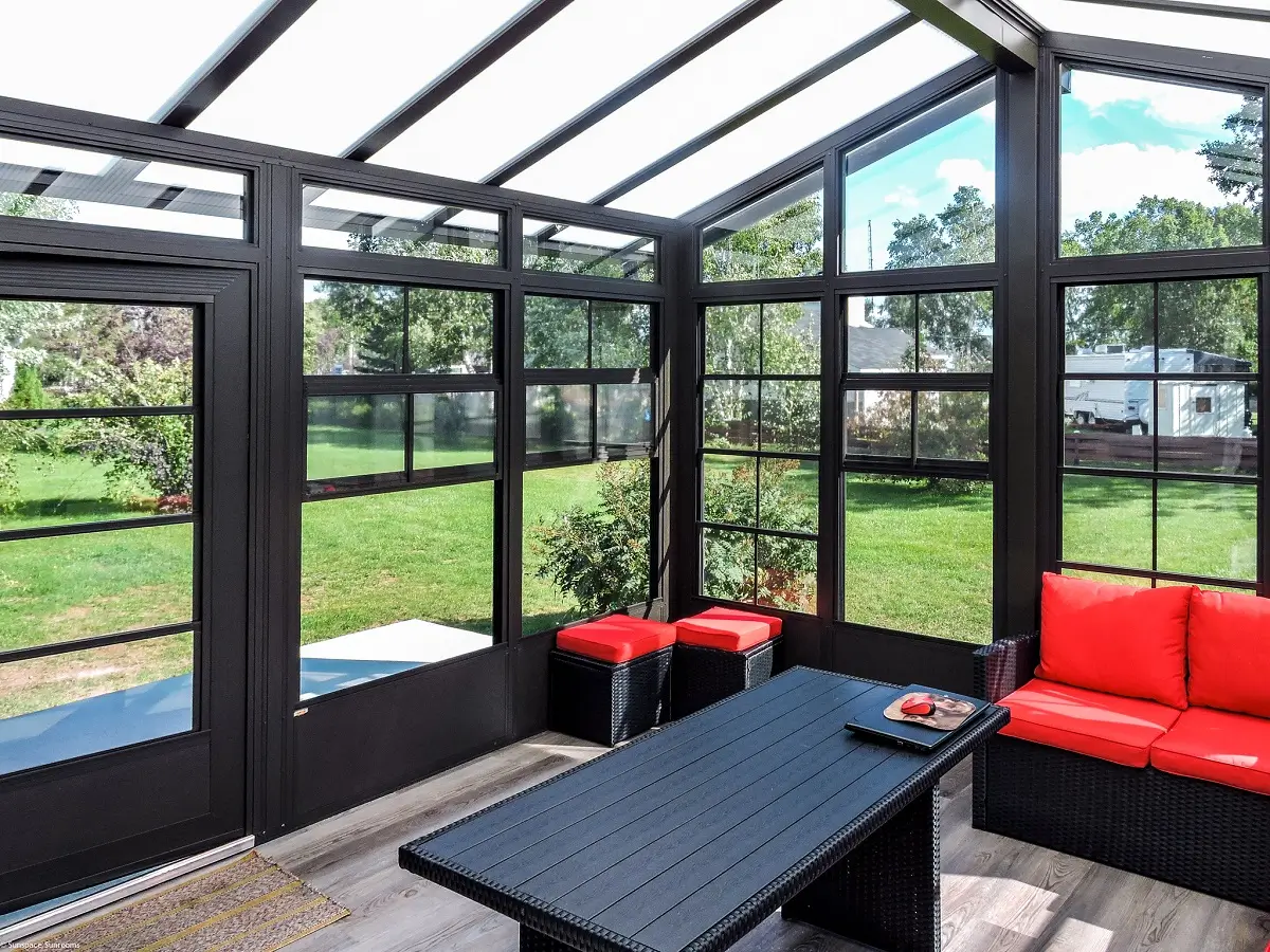 Modern 3 season sunroom with black frames, vinyl windows, glass roof, and red cushions.