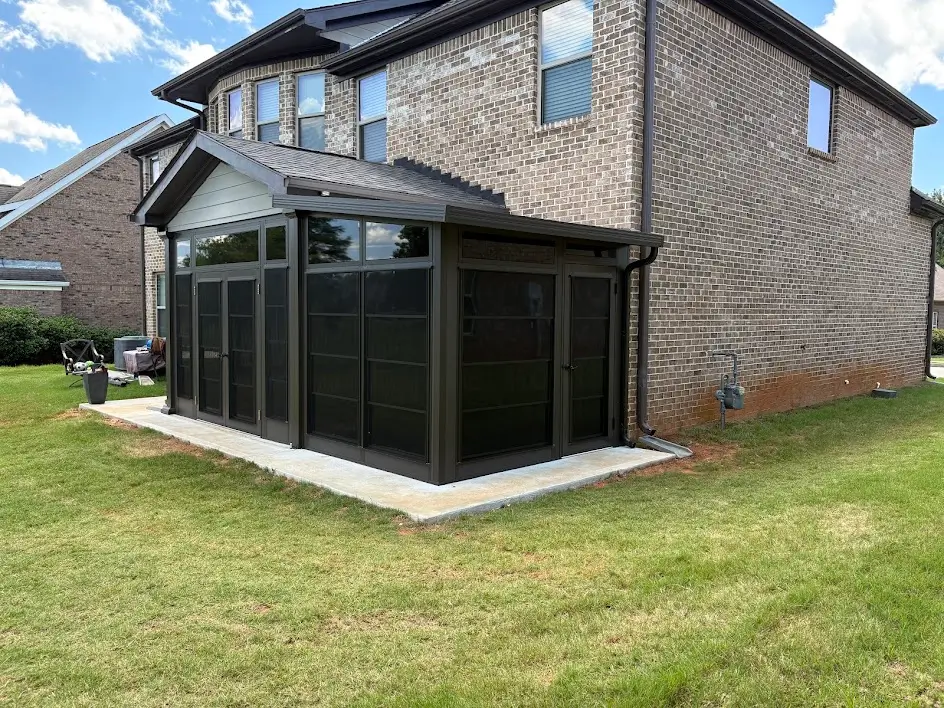 A dark bronze Sunspace sunroom addition built onto the back of a brick house.