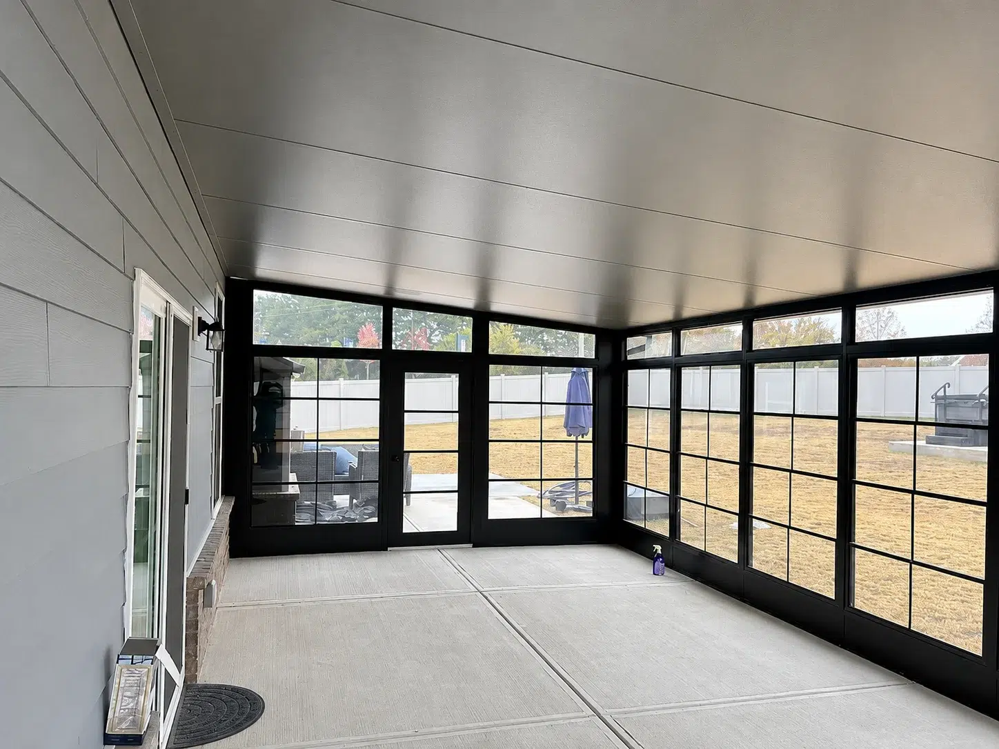 Interior view of a black screen room enclosure with large screened windows, concrete floor, and backyard views for Myrtle Beach outdoor living.