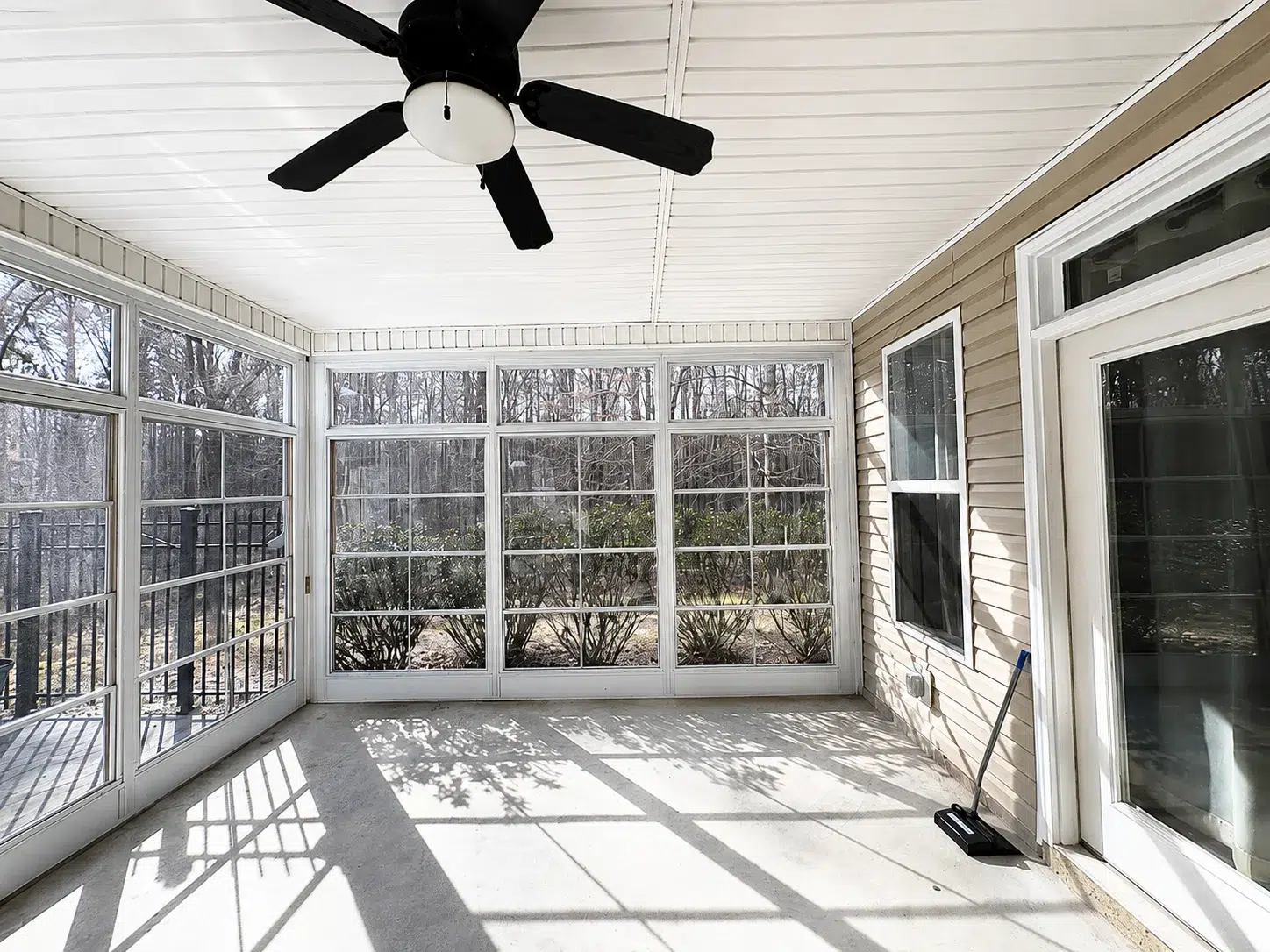 Bright enclosed screen room with large windows, white ceiling, ceiling fan, and outdoor views for a South Atlanta home upgrade.