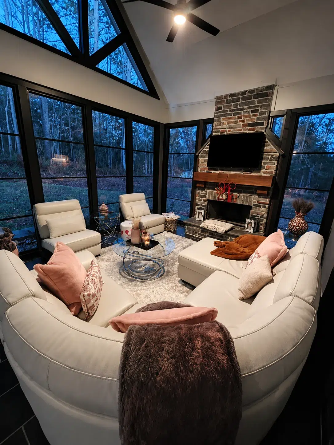Luxury sunroom interior with black-framed windows, vaulted ceiling, fireplace, and cozy seating for protected Myrtle Beach outdoor living.