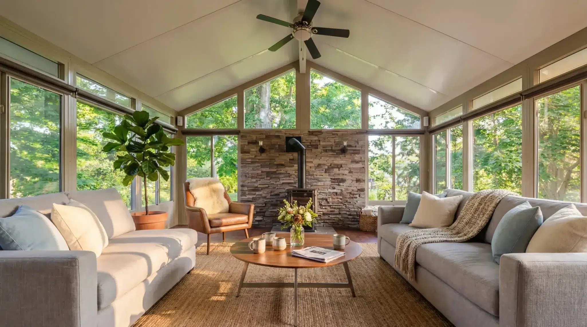 Bright Sunspace Model 400 insulated sunroom interior featuring comfortable couches and stone fireplace.