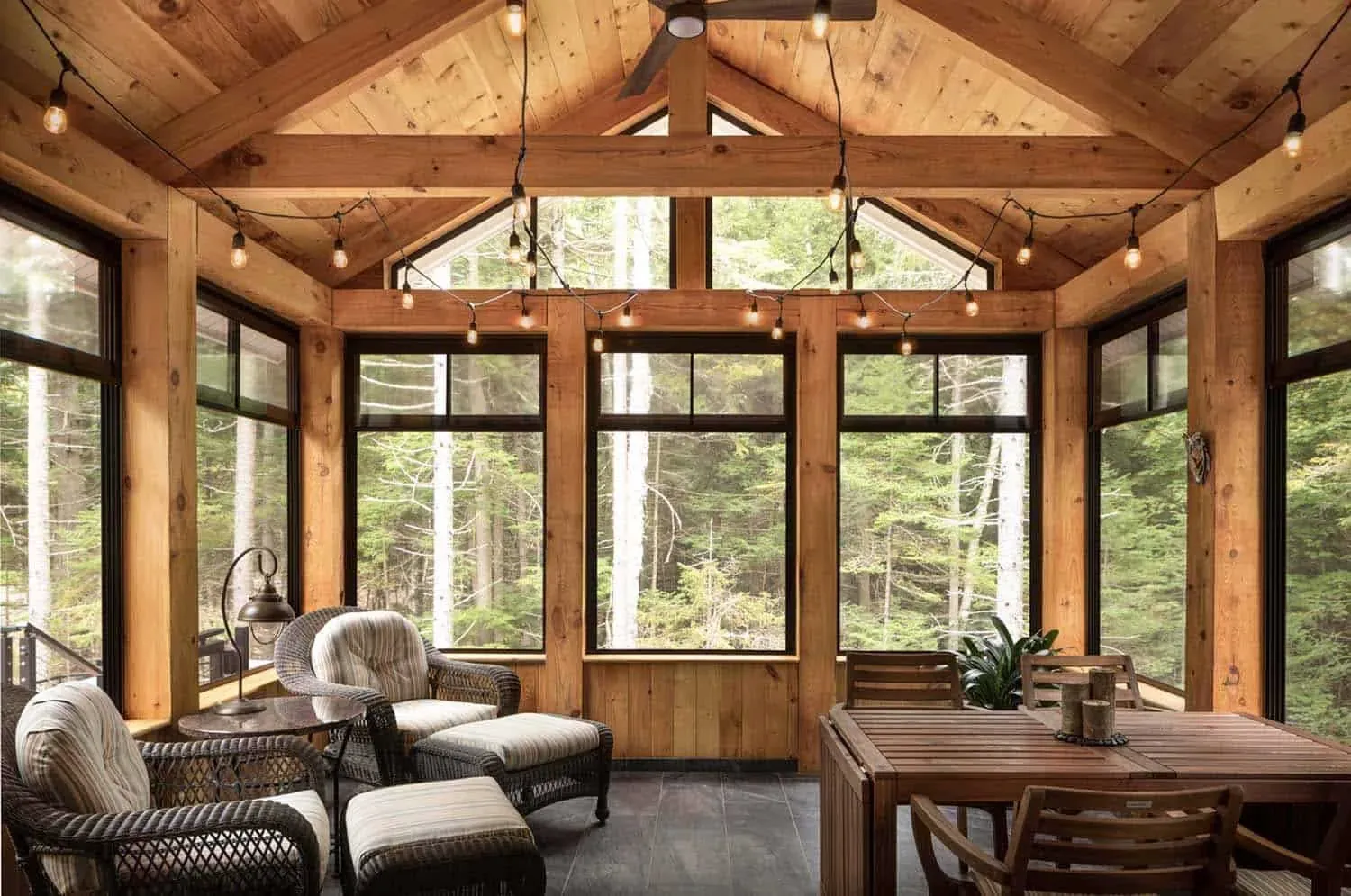 A dark gray house features a black-framed WeatherMaster porch enclosure system next to an open backyard lawn.