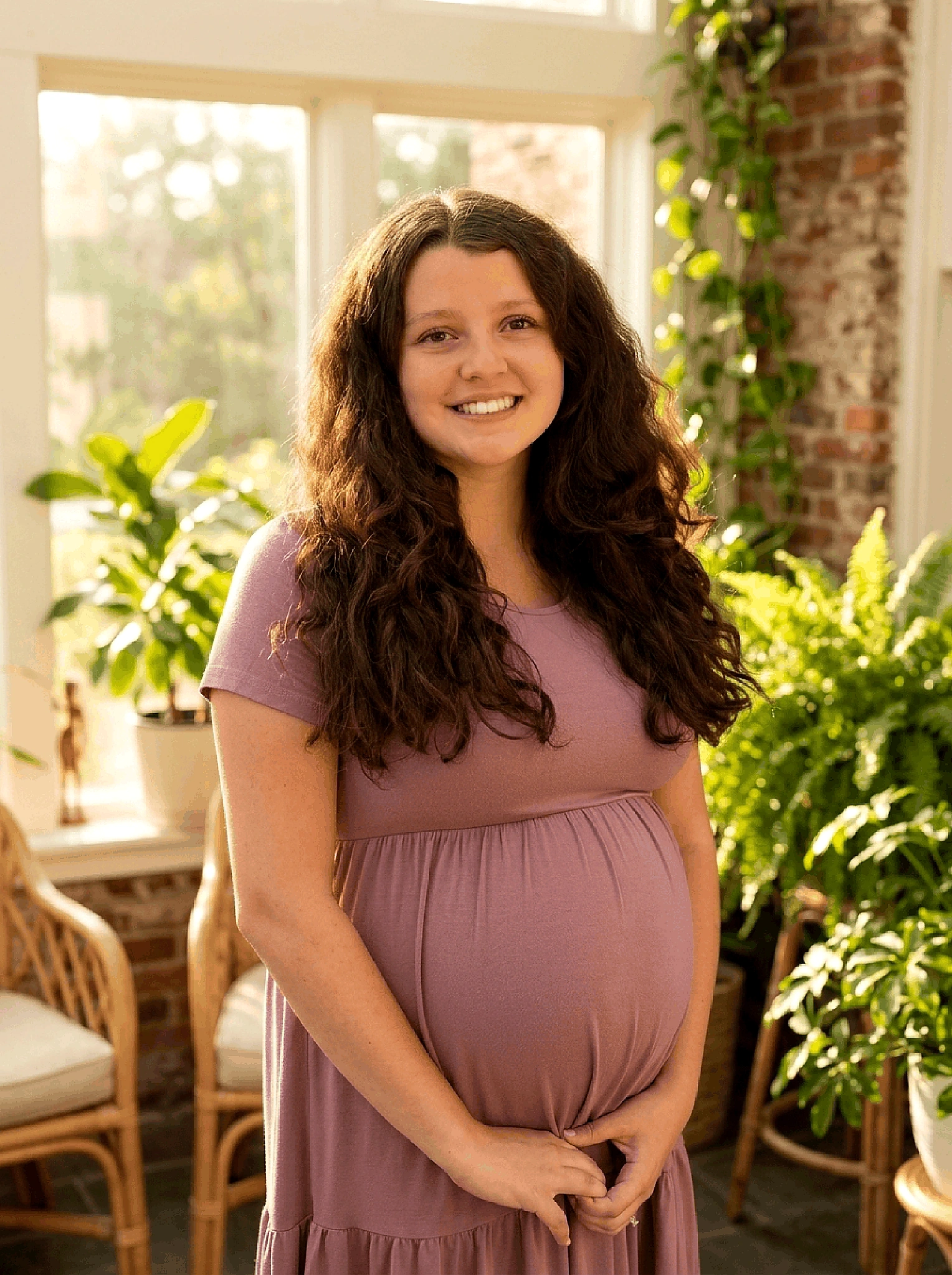 Julia Martinez, member of Sunspace South Atlanta posing happily in a brightly lit, cozy sunroom setting.