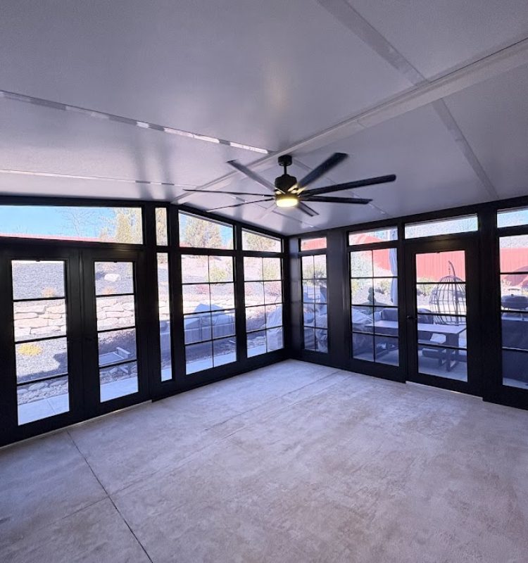 Modern Sunspace sunroom with black glass doors, beige tile flooring, and a large ceiling fan.