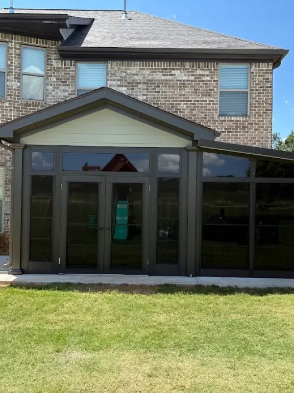 Modern dark gray Sunspace sunroom extension built on a brick home patio.